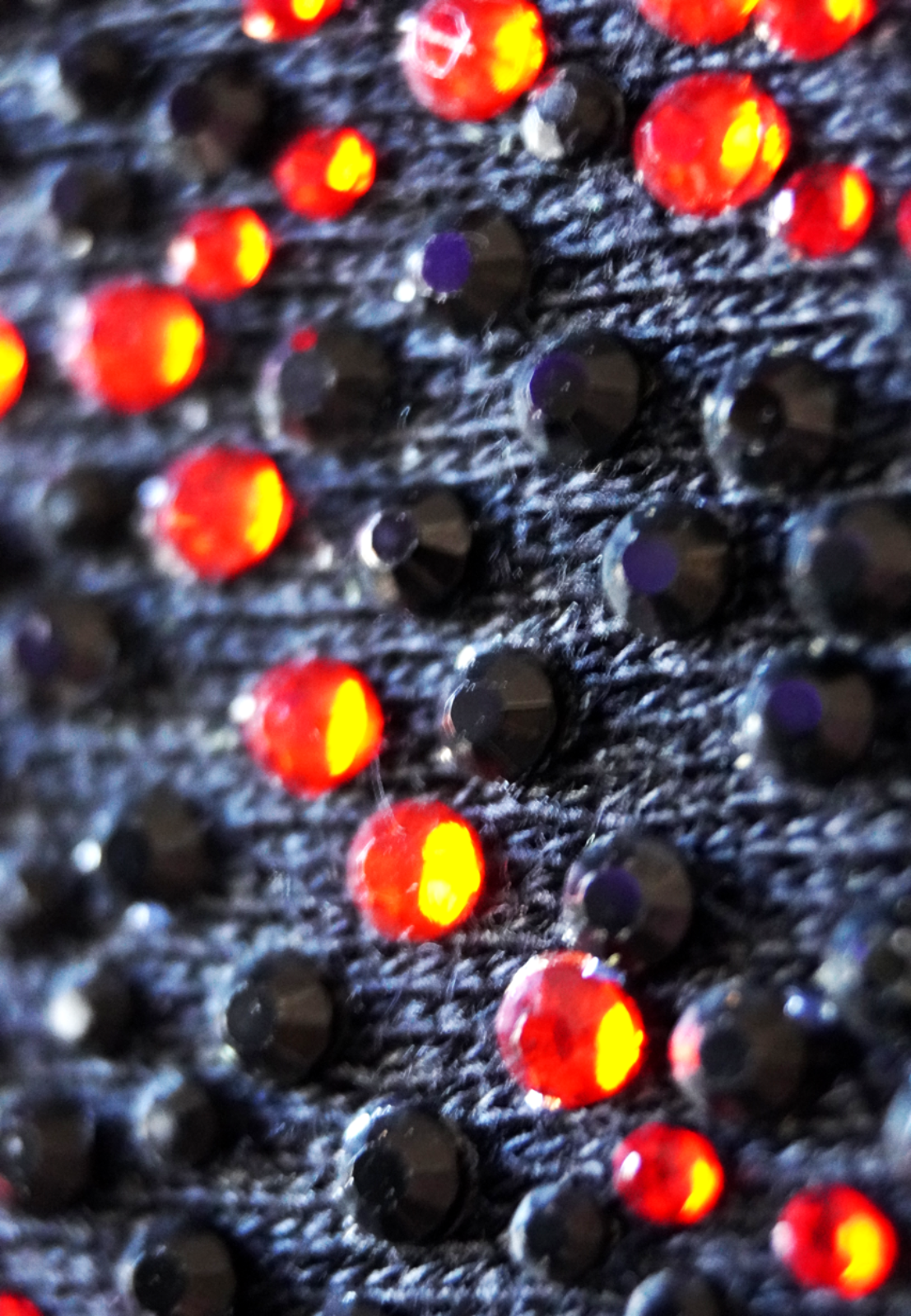 Rhinestones, Specialty Application, Close-up of a garment surface with red and black rhinestones. 